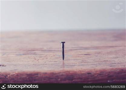 Close up on a nail hammered into a wooden table