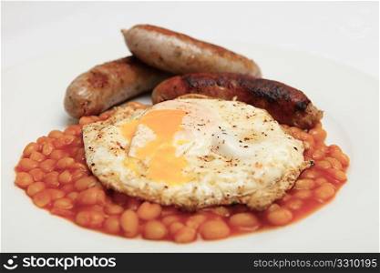 Close-up on a typical British breakfast of baked beans, egg and sausage on a white plate.