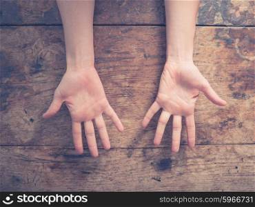 Close up on a woman showing her palms at a wooden table
