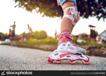 Close up on child&rsquo;s legs wearing roller blades skates learning to ride on the asphalt in the school yard activities