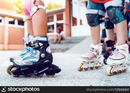Close up on children&rsquo;s legs wearing roller blades skates learning to ride on the asphalt in the school yard activities