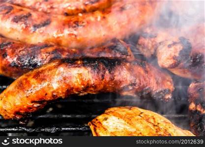 Close up on details of homemade chicken, pork steak and sausages on barbecue grill. Barbecue, grill and food concept.