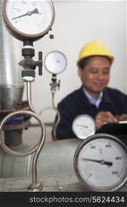 Close- up on gas gauges with worker in the background in a gas plant, Beijing, China