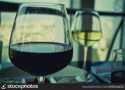 Close up on glasses with red and white wine on white table.