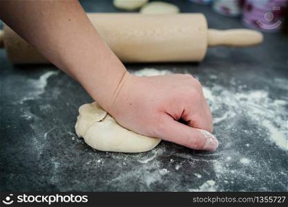 Close up on hand of unknown caucasian woman female girl making bread or pastry knead the dough kneading on the kitchen table at home side view