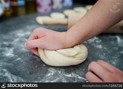 Close up on hand of unknown caucasian woman female girl making bread knead the dough kneading on the kitchen table at home side view