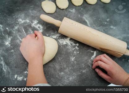 Close up on hand of unknown caucasian woman female girl making bread knead the dough kneading on the kitchen table at home top view