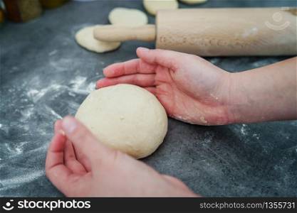 Close up on hand of unknown caucasian woman female girl making bread knead the dough kneading on the kitchen table at home top view