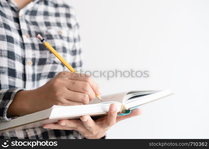 close up on hand writing paper notebook. On young woman left hand holding notebook and right hand writing diary.