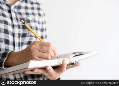 close up on hand writing paper notebook. On young woman left hand holding notebook and right hand writing diary.