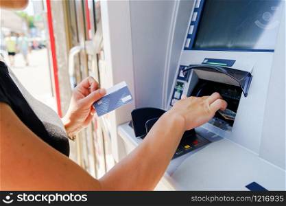 Close up on hands of caucasian woman at the atm taking paying bills money at the cash machine bank using debit card