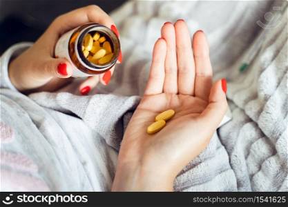 Close up on hands of unknown caucasian woman holding a bottle with medicine drugs - Female taking supplement vitamins mineral while being sick at home - healthcare medicine covid-19 pandemic concept