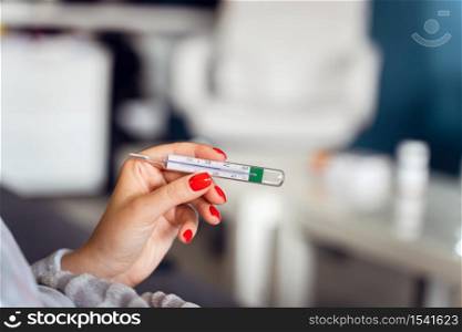 Close up on hands of unknown caucasian woman holding thermometer while lying in bed - Adult female checking and measuring body temperature having fever at home - Covid-19 pandemic concept healthcare