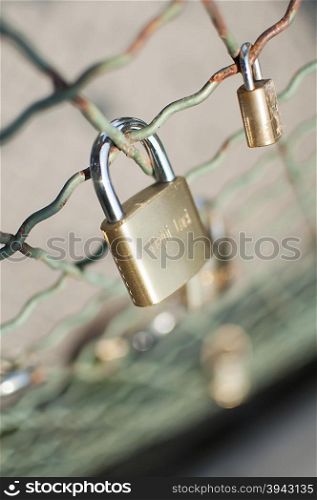 Close-up on lockers symbolizing everlasting love on a bridge fence