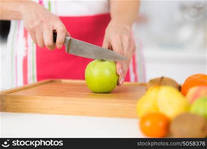 close-up on mature female hands slicing apples on chopping board