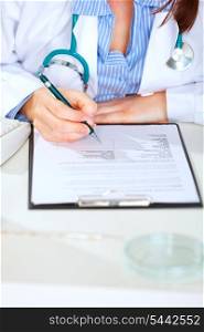 Close up on medical doctor woman sitting at table and working with document&#xA;