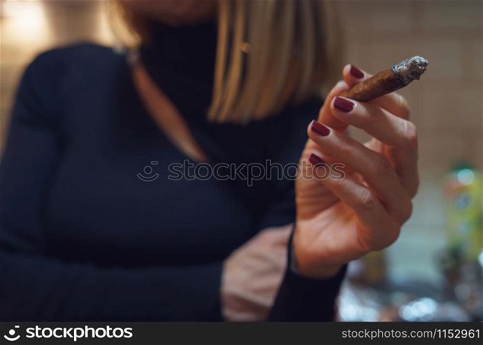 Close up on midsection of caucasian woman holding cigarillo in hand smoking smoke