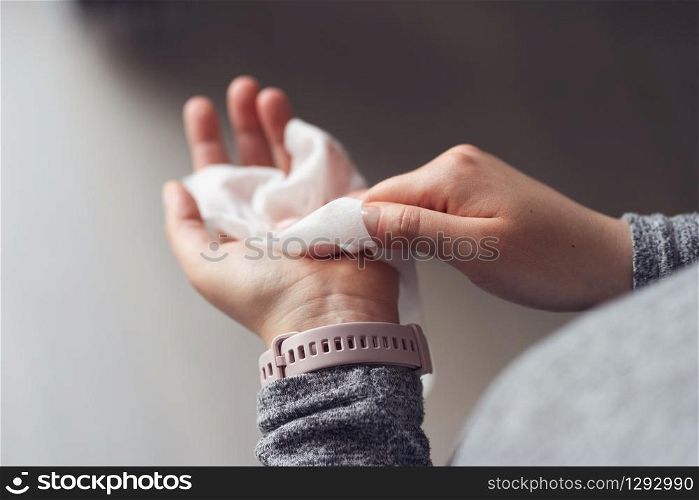 Close up on midsection of young caucasian woman hands wiping using white alcohol tissue cleaning napkin disinfection from virus and bacteria in day at home or office high angle view