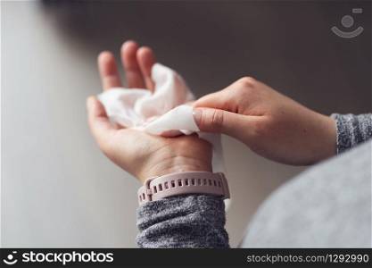 Close up on midsection of young caucasian woman hands wiping using white alcohol tissue cleaning napkin disinfection from virus and bacteria in day at home or office high angle view
