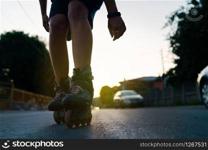 Close up on rollerblade roller blade skates man legs against sun in the summer evening riding on the street
