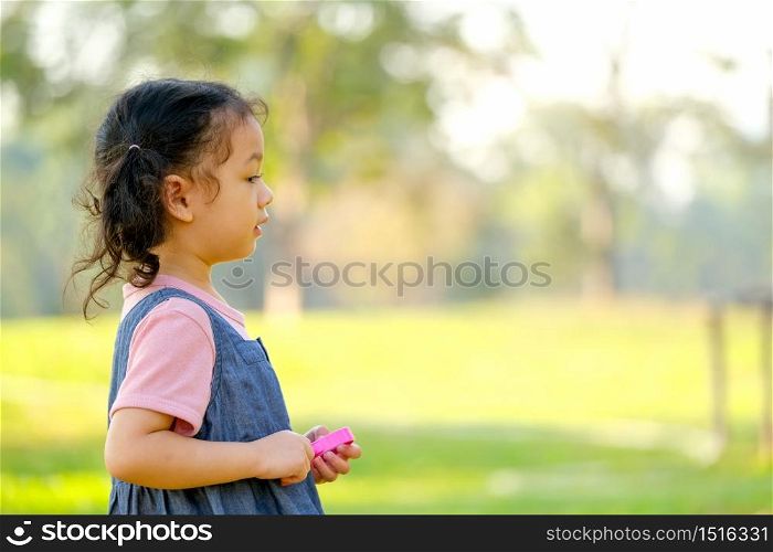 Close up on side of little girl enjoy with playing in the green garden with morning light and copy space.