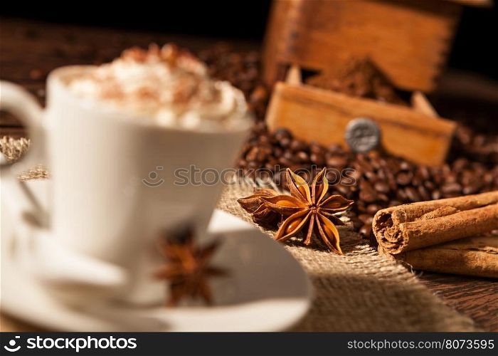 Close-up on star anise and cinnamon sticks with coffee cup and whipped cream. Close-up on star anise and cinnamon sticks with coffee cup