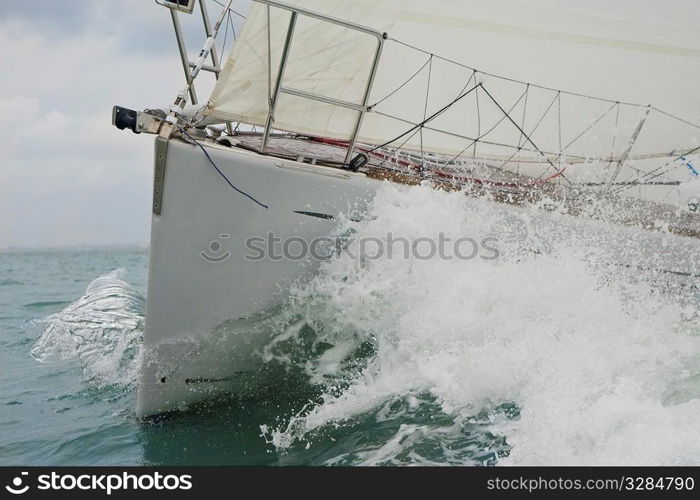 Close up on the bow of a sailing yacht breaking through a wave