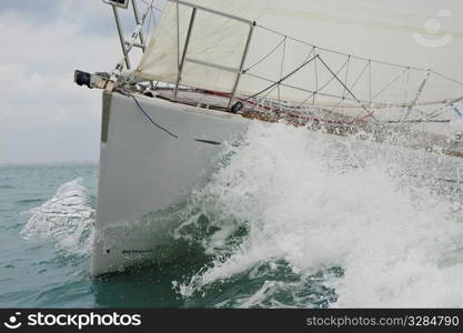 Close up on the bow of a sailing yacht breaking through a wave