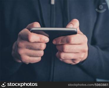 Close up on the hands of a young man using a smartphone