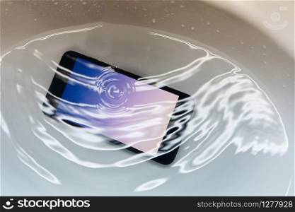 Close-up on Water Proof Smartphone Drop in to the Sink with Full of Water
