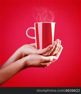 Close up on woman's hands holding red cup of hot coffee isolated on red background, tasty hot drink, time for a break