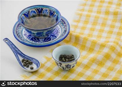 close up oolong tea cup with spoon tablecloth against white background