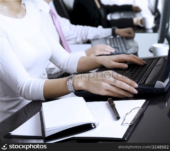 Close-up os human hands. Young office workers are typing on keyboards in front of their office computers.