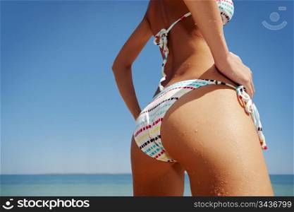 close up outdoor shot of young woman in white bikini, sunbathing at sea shore