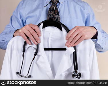 Close up partial view of medical doctor holding consultation white coat with stethoscope in front of him.