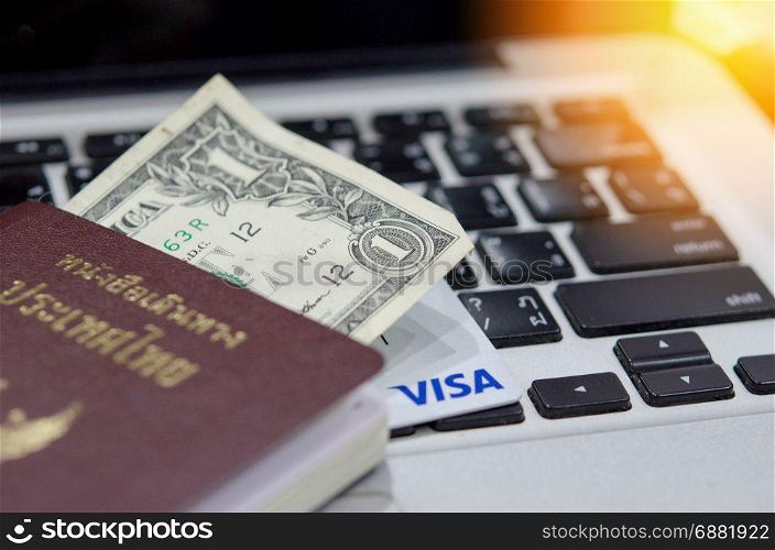 Close up Passport and money on the keyboard laptop.Travel concept