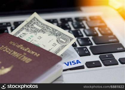 Close up Passport and money on the keyboard laptop.Travel concept