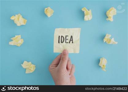 close up person holding idea paper with crumpled ball papers blue backdrop