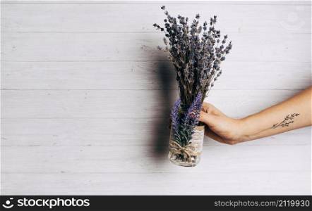 close up person holding lavender bouquet against wooden backdrop