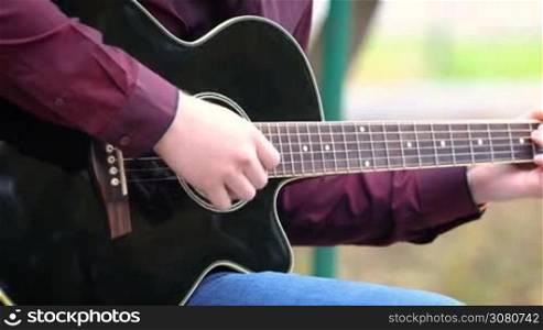 Close up person man&acute;s hands playing acoustic guitar artist musician outdoors.