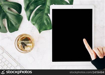 close up person pointing finger digital tablet with tea glass marble textured backdrop