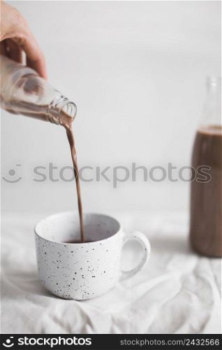 close up person pouring chocolate milkshake white cup