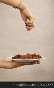 close up person s hand garnishing mexican beef dish
