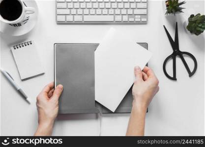 close up person s hand inserting blank white paper gray cover workspace desk