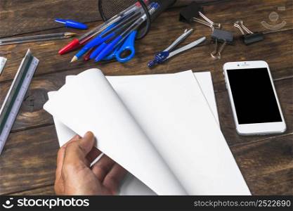 close up person turning page with stationeries mobile table