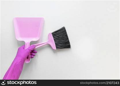 close up person with purple gloves holding small broom