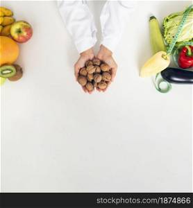 close up person with vegetables holding nuts