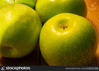 Close up photo of green apples on a wooden board.