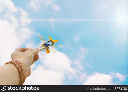 Close up photo of man's hand holding toy airplane against blue sky with white clouds. close up photo of man's hand holding toy airplane against blue sky
