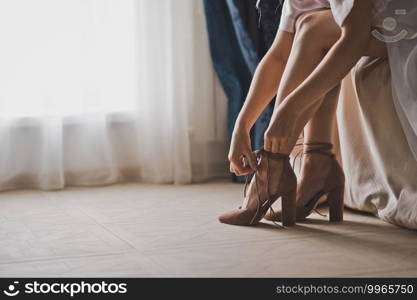 Close-up photo of the brides legs at the big window.. The bride is buttoning her shoes 2403.